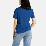 The back of Sophia (A woman with long black hair) wearing the No Limbits Adaptive Women's Navy Sensory Tee.