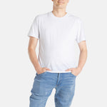 A white man with short brown hair wears a white t-shirt.