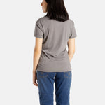 The back of Sophia (A woman with long black hair) wearing the No Limbits Adaptive Women's Charcoal Sensory Tee.