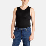 A white man with short brown hair wears a black tank top and denim jeans.