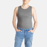 A white man with short brown hair wears a charcoal-gray tank top and denim jeans.