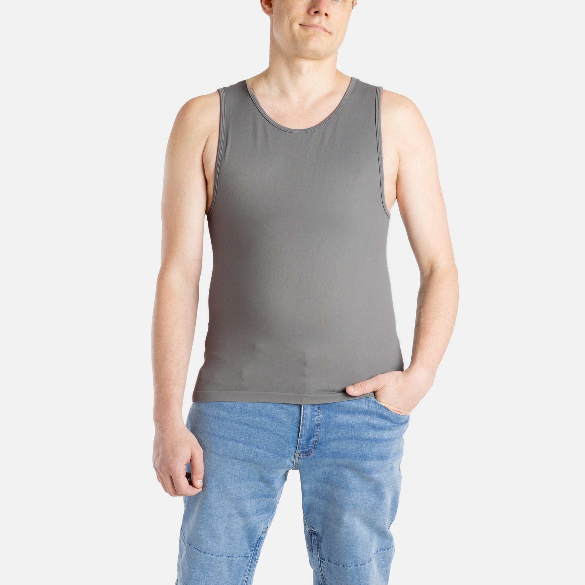 A white man with short brown hair wears a charcoal-gray tank top and denim jeans.