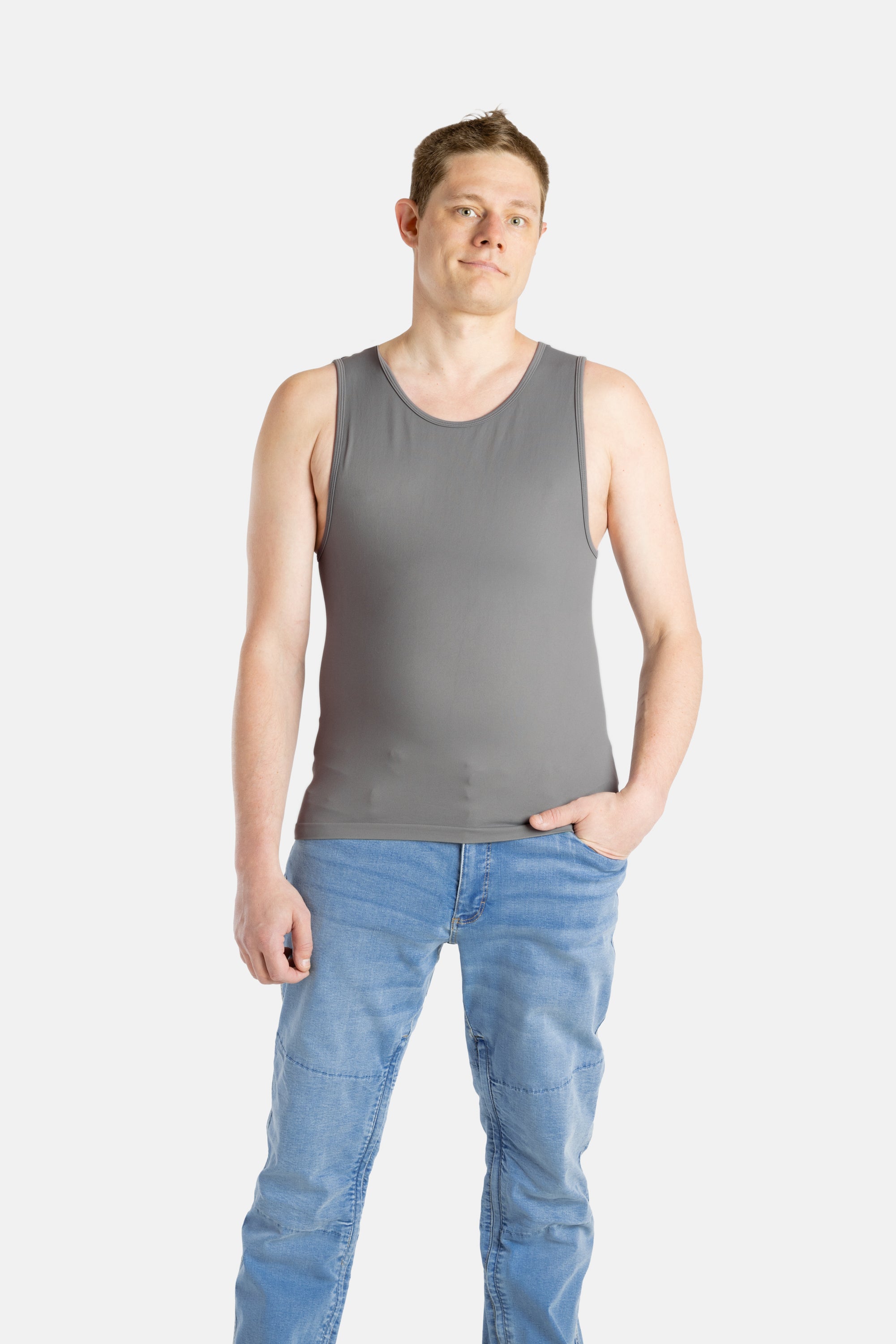 A white man with short brown hair wears a charcoal-gray tank top and denim jeans.
