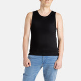 A white man with short brown hair wears a black tank top and denim jeans.