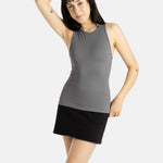 A white woman with long black hair and hoop earrings wears a black tank top and a short black skirt.