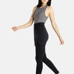 A white woman with long black hair and hoop earrings wears a charcoal tank top and black leggings.
