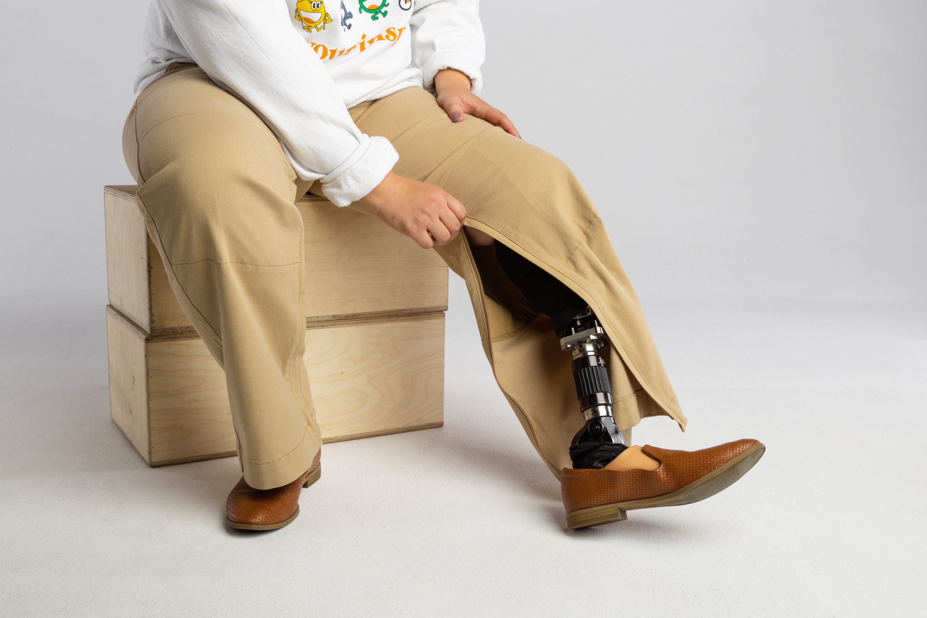 The zipper of the  No Limbits Adaptive Women's Khaki Unlimbited Pants is zipped up to reveal a prosthetic leg  on the wearer.