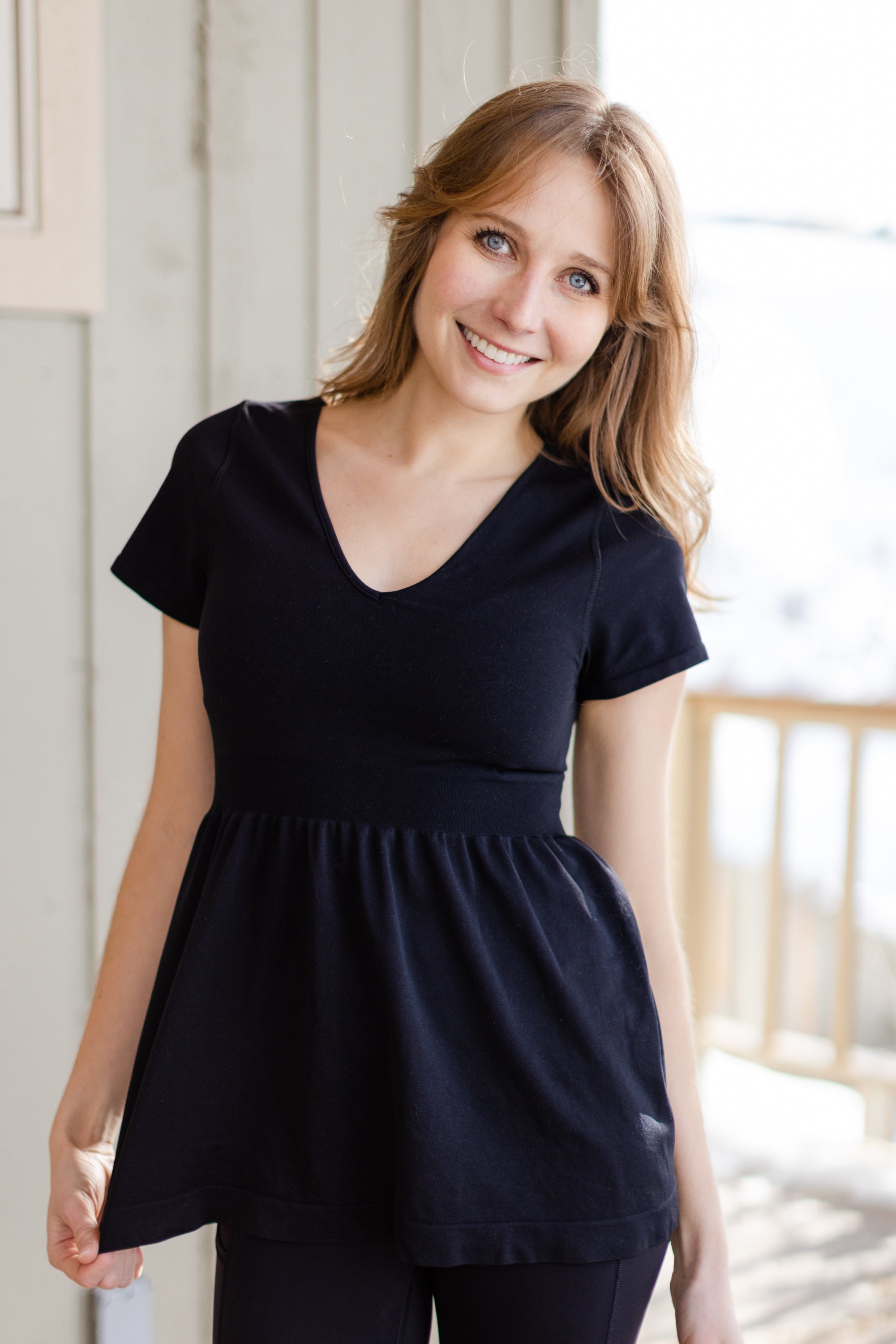 A white woman with long blonde hair is wearing the No Limbits Adaptive Women's Black Sensory Blouse.