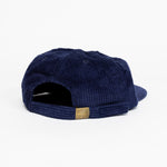 The back of a dark blue baseball cap that has a illustration of the moon and the stars that says in white font "Sky's the Limbit."
