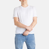 A white man with short brown hair wears a white t-shirt.