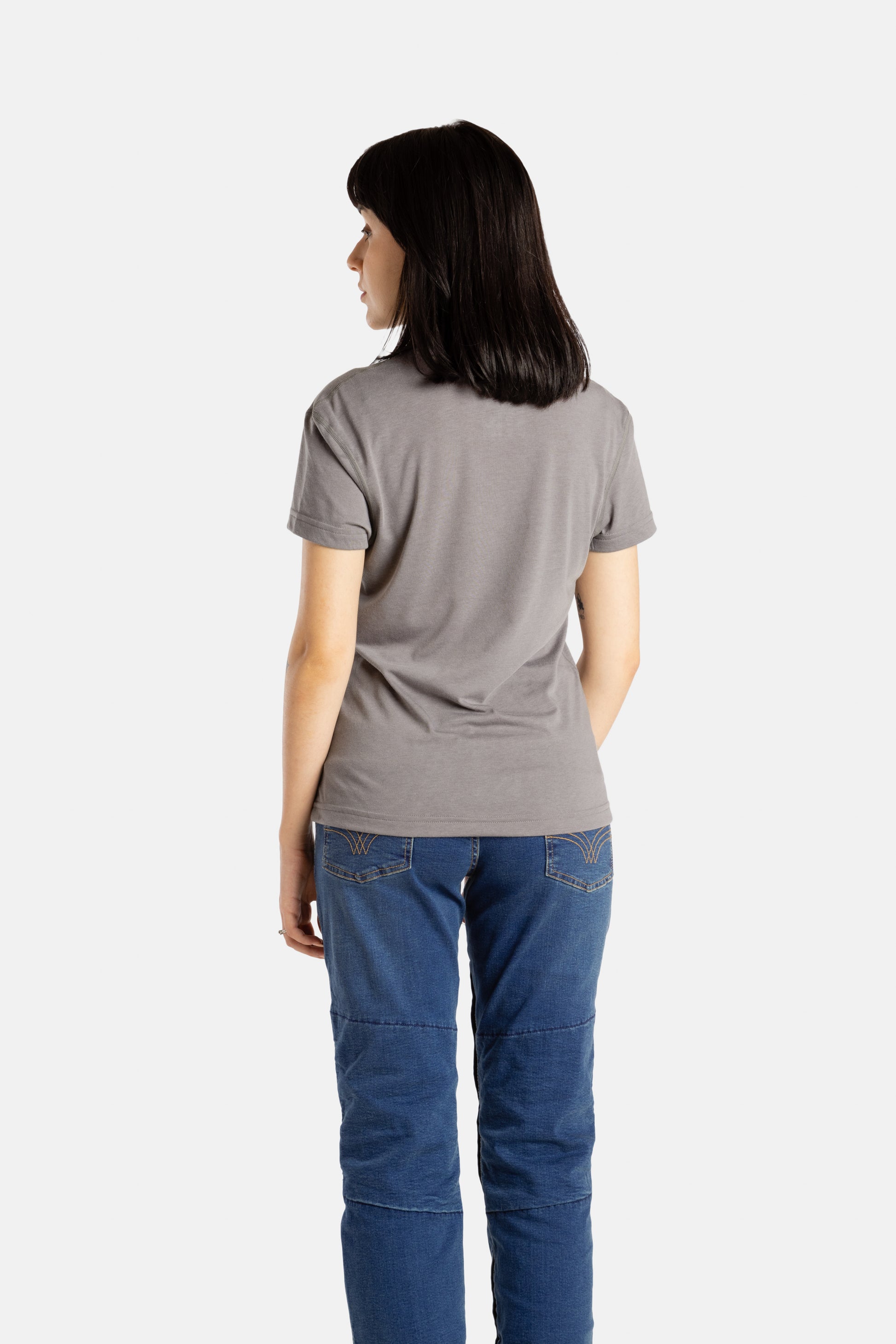 The back of Sophia (A woman with long black hair) wearing the No Limbits Adaptive Women's Charcoal Sensory Tee.