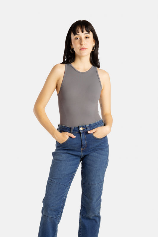 A white woman with long black hair and hoop earrings wears a charcoal tank top and denim jeans.