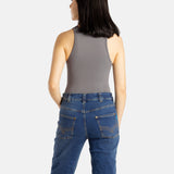 The back of a white woman with long black hair and hoop earrings wears a black tank top and denim jeans.