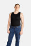 A white man with short brown hair wears a black tank top and denim jeans.