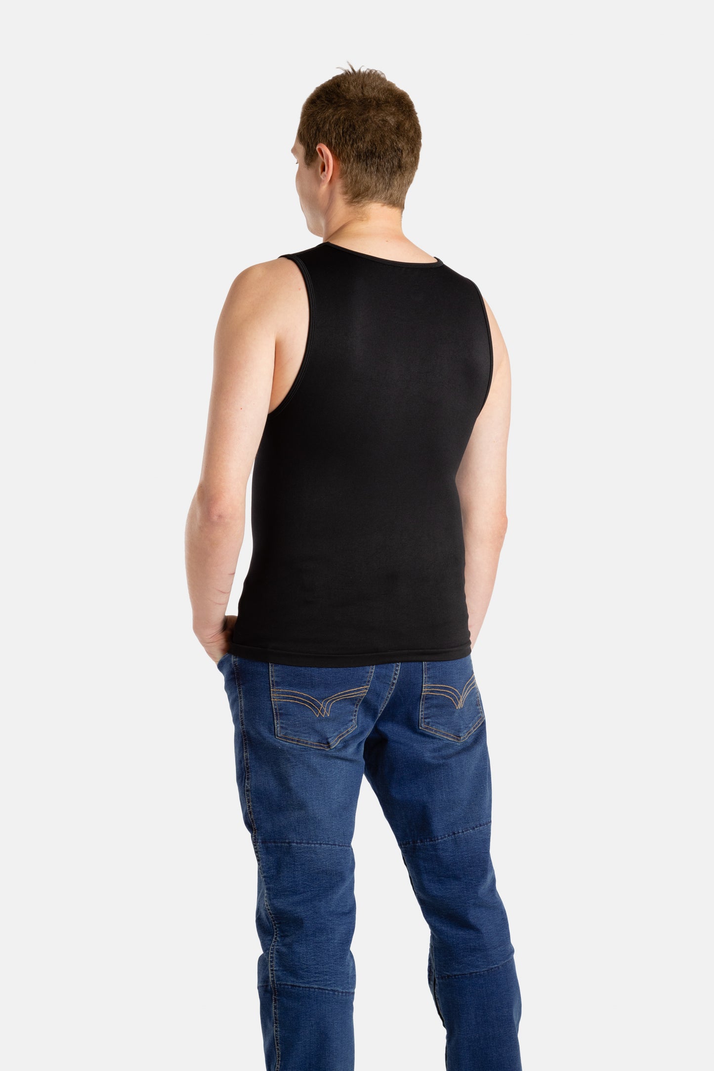 The back of a white man with short brown hair wearing a black tank top and denim jeans.