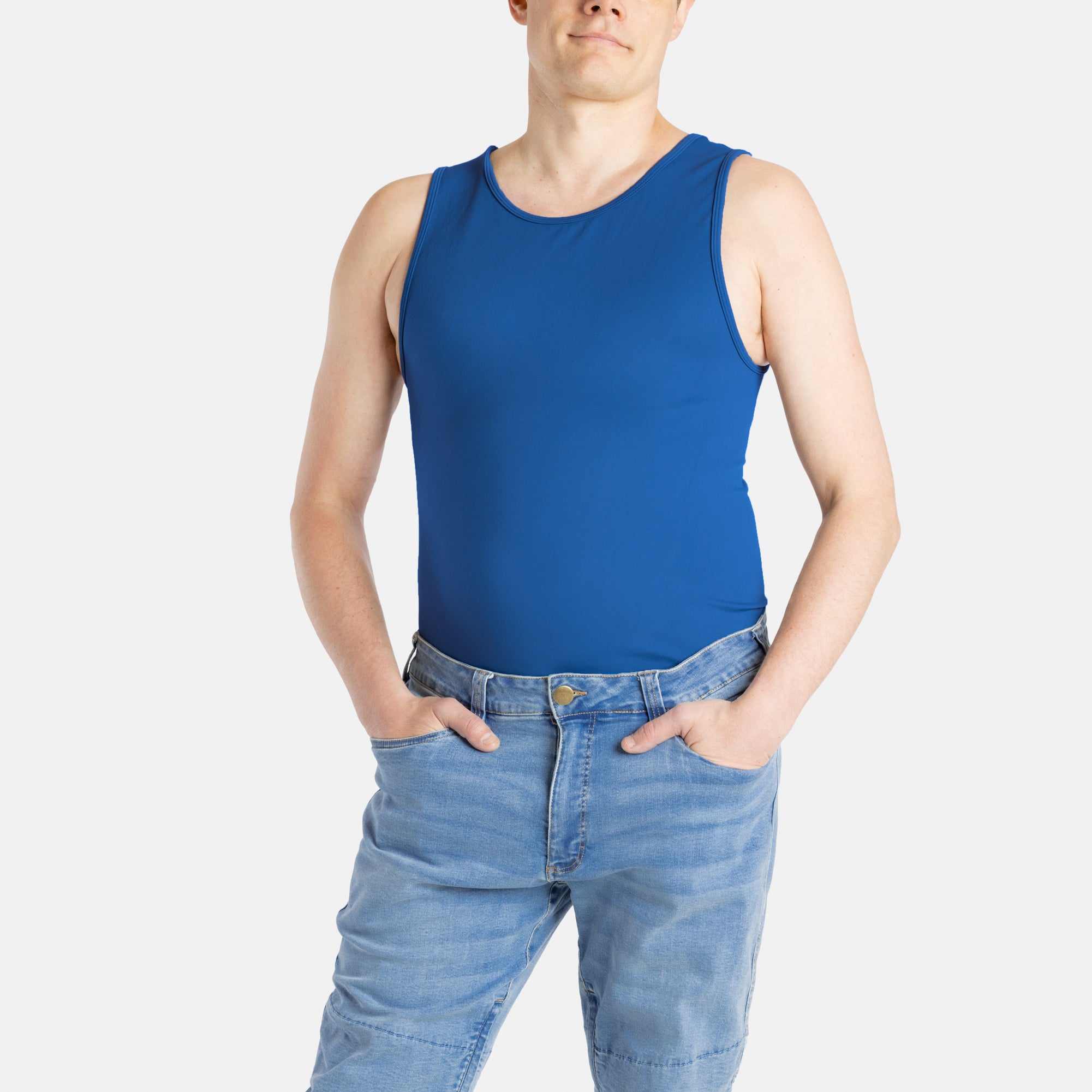A white man with short brown hair wears a navy tank top and denim jeans.