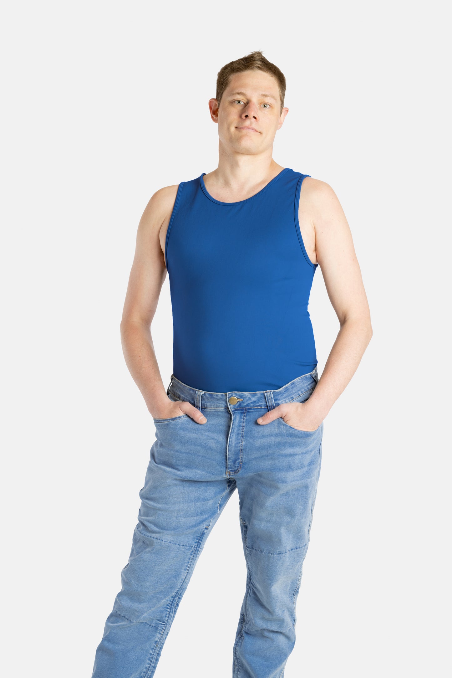 A white man with short brown hair wears a navy tank top and denim jeans.