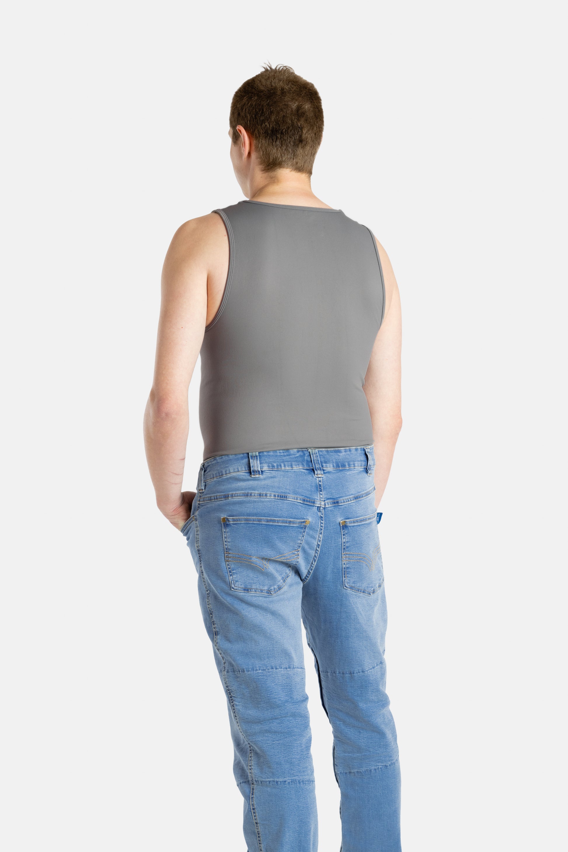 A white man with short brown hair wearing a charcoal-gray tank top and denim jeans.