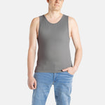 A white man with short brown hair wears a charcoal-gray tank top and denim jeans.