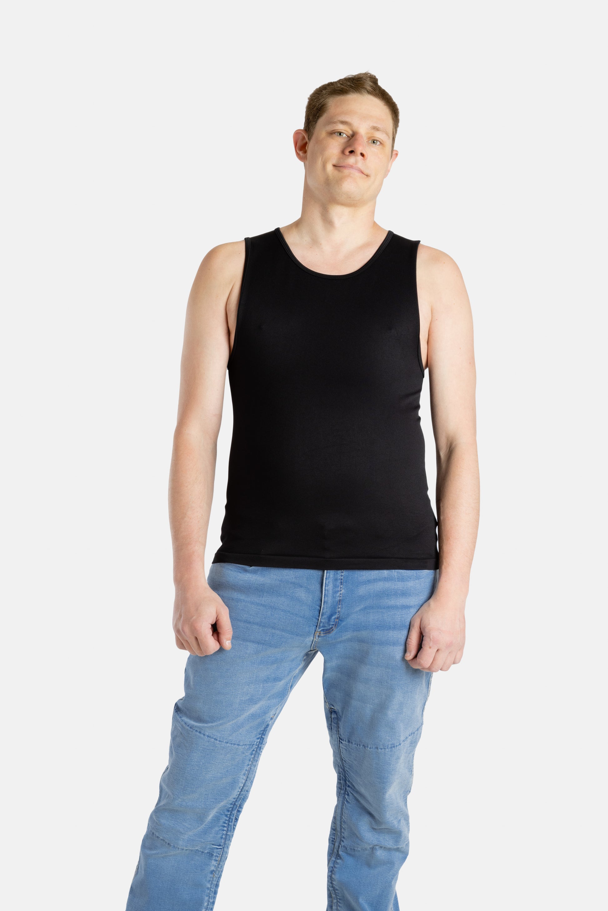 A white man with short brown hair wears a black tank top and denim jeans.