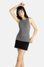 A white woman with long black hair and hoop earrings wears a black tank top and a short black skirt.