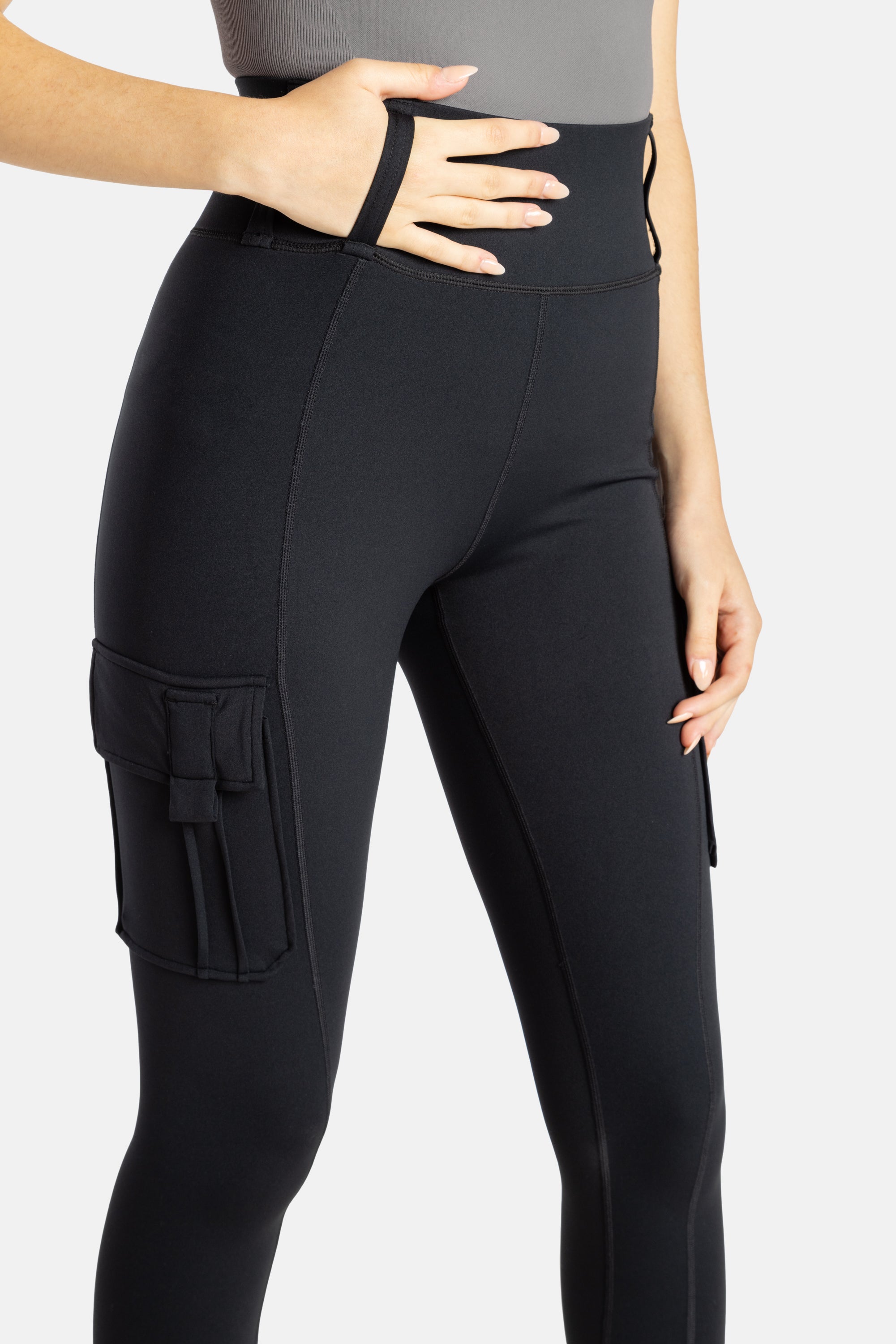 The close up of the black leggings. A hand is in the loop on the top of the pants.