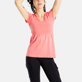 Sophia (A woman with long black hair) is wearing the No Limbits Adaptive Women's Coral Sensory Blouse with black leggings. She is pulling her hair back.