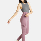 A white woman with long black hair and hoop earrings wears a charcoal tank top and mauve (Pinkish lavender) leggings.