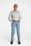 A white, elderly man with a mustache wears the Men’s Light Wash Unlimbited Pants, with a long-sleeved gray shirt, a brown belt, and brown shoes.