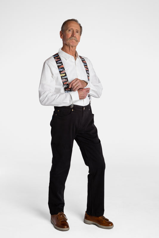 A white, elderly man with a mustache wears the No Limbits Adaptive Men's Black Unlimbited Pants, with a white shirt, colorful suspenders, and brown shoes.