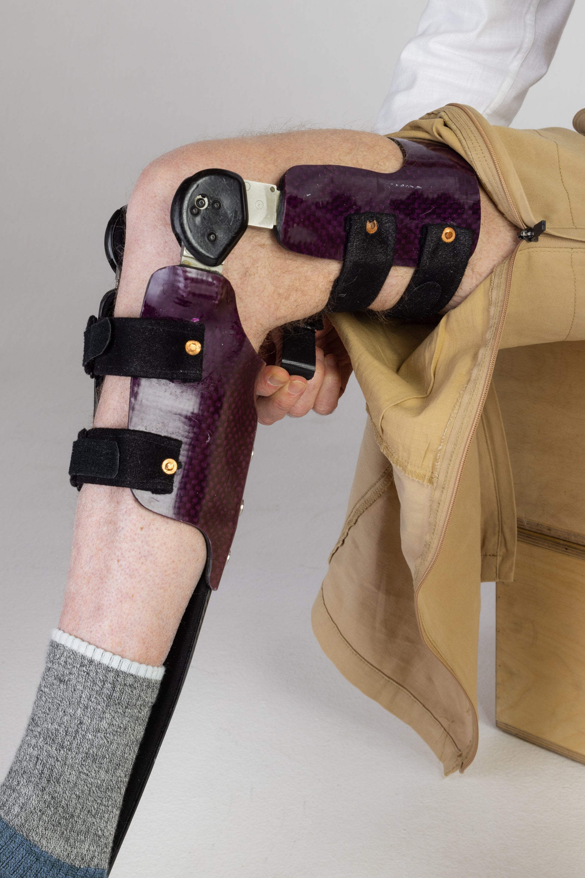 The zipper of the  No Limbits Adaptive Men's Khaki Unlimbited Pants is zipped up to reveal a knee brace on the wearer.
