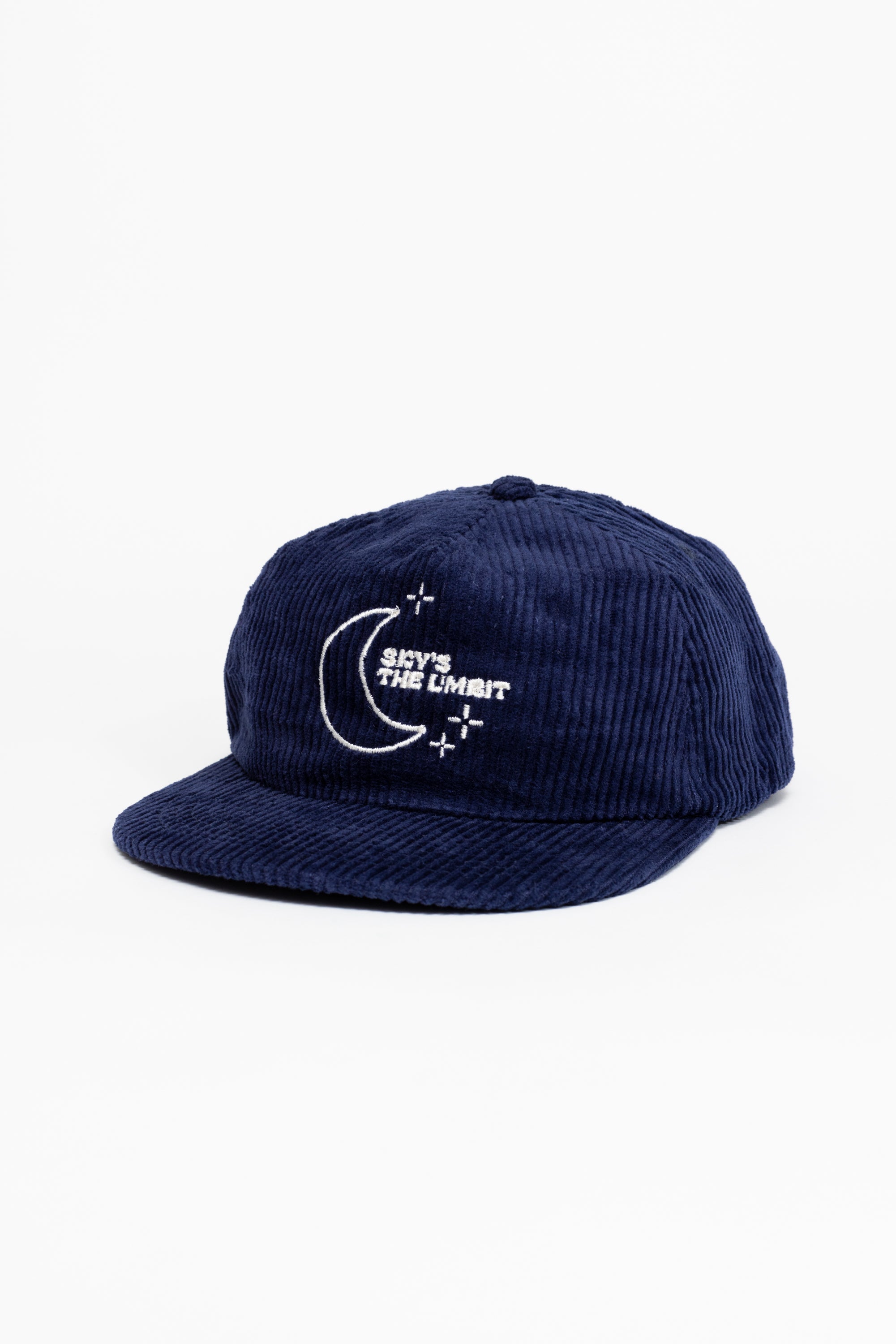 A dark blue baseball cap that has a illustration of the moon and the stars that says in white font "Sky's the Limbit."